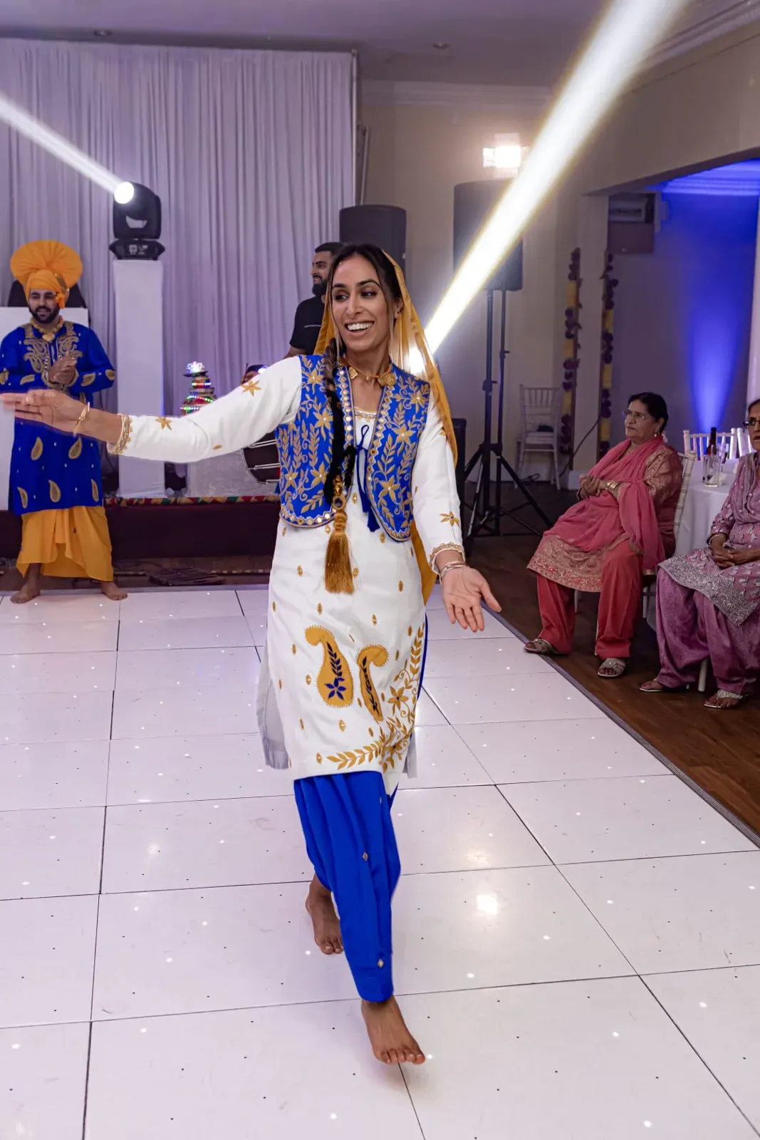 Female bhangra dancer in white and blue performing at a wedding