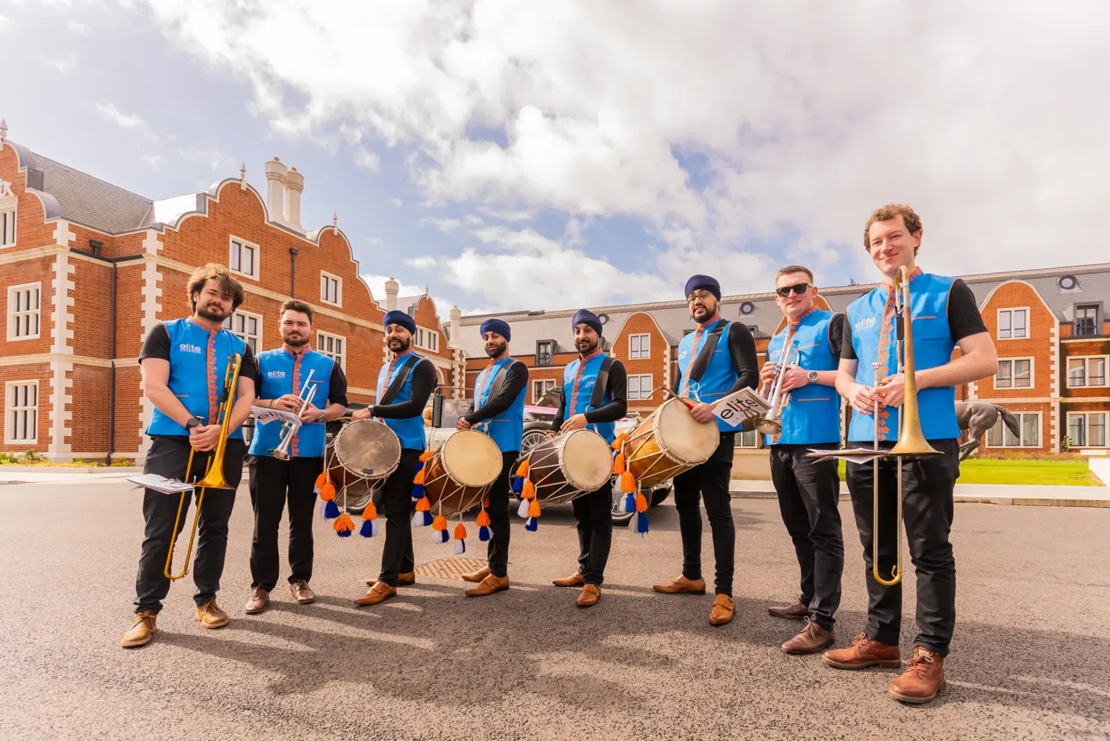 Dhol players and a brass band baja line-up in matching blue jackets