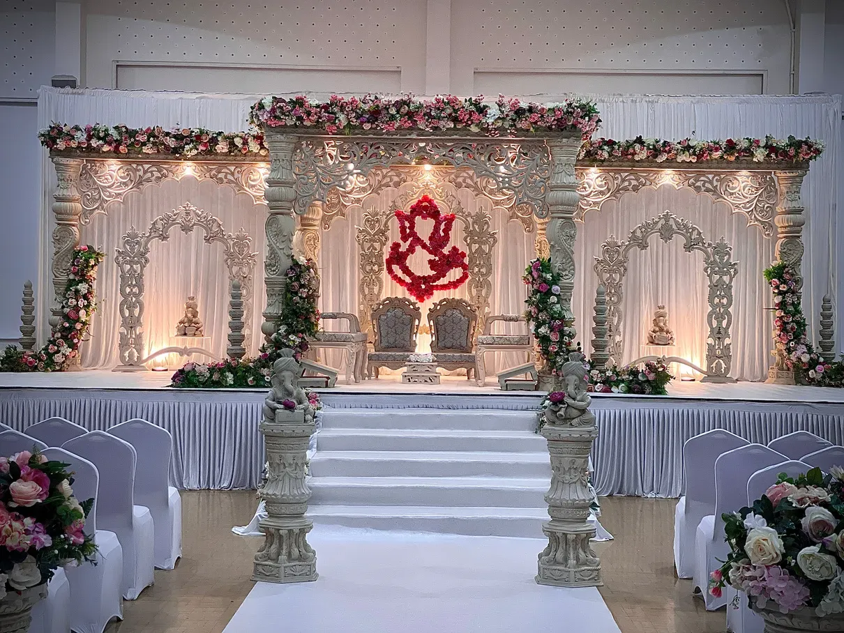 Wide mandap stage with carved arches and a Ganesh backdrop