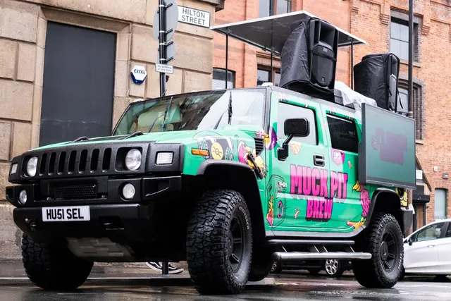 Wrapped DJ truck on a city street with roof speakers