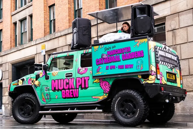 Brightly wrapped DJ truck with speakers and a DJ on the roof