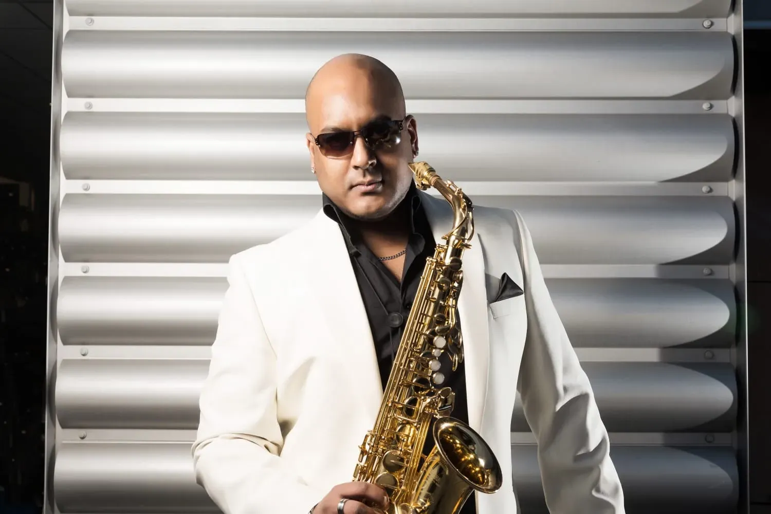 Saxophonist in a white jacket holding a gold saxophone