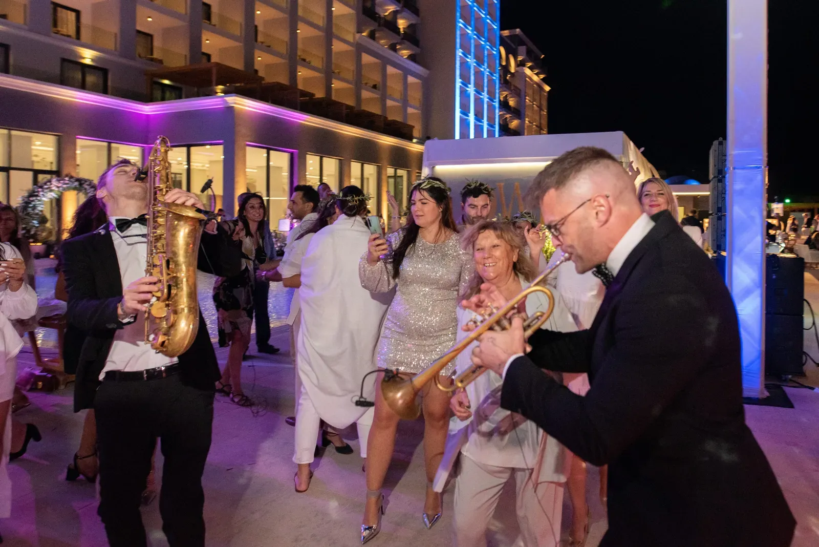 Sax and trumpet players dancing among wedding guests