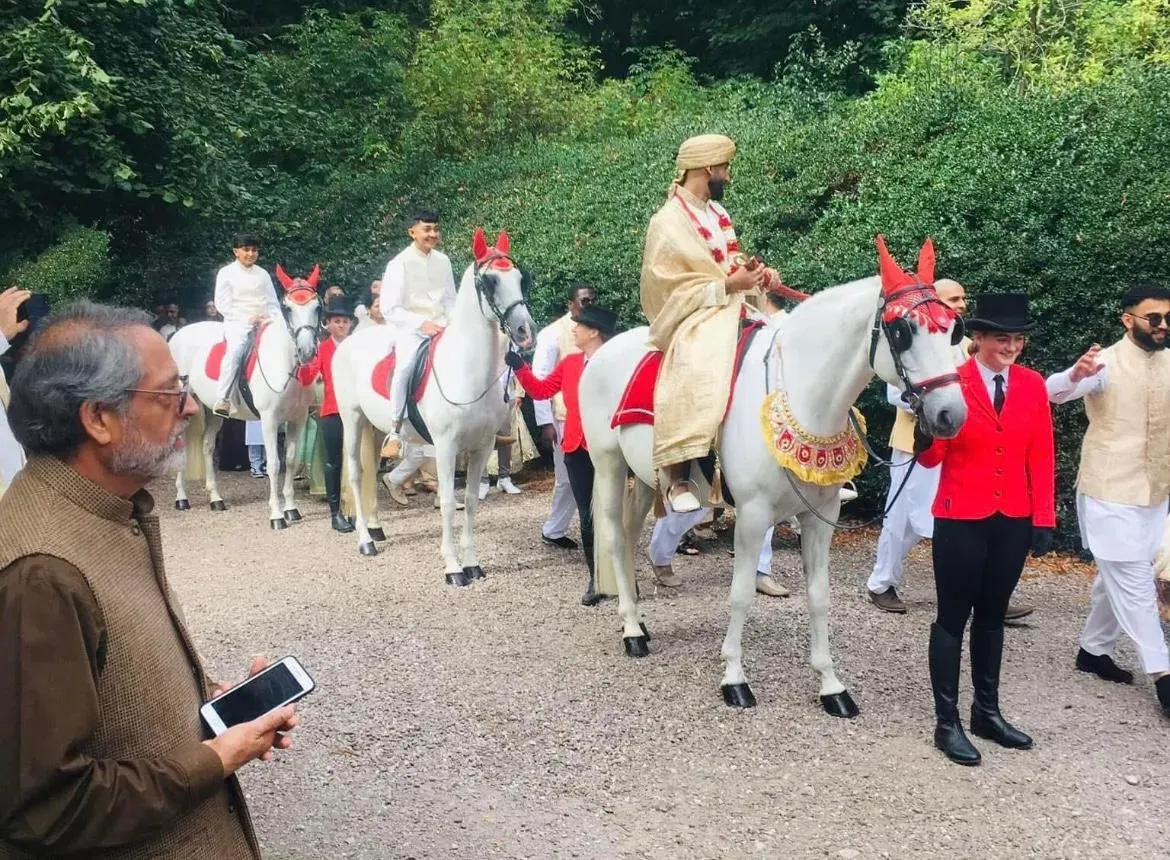 Baraat procession with decorated white horses and handlers